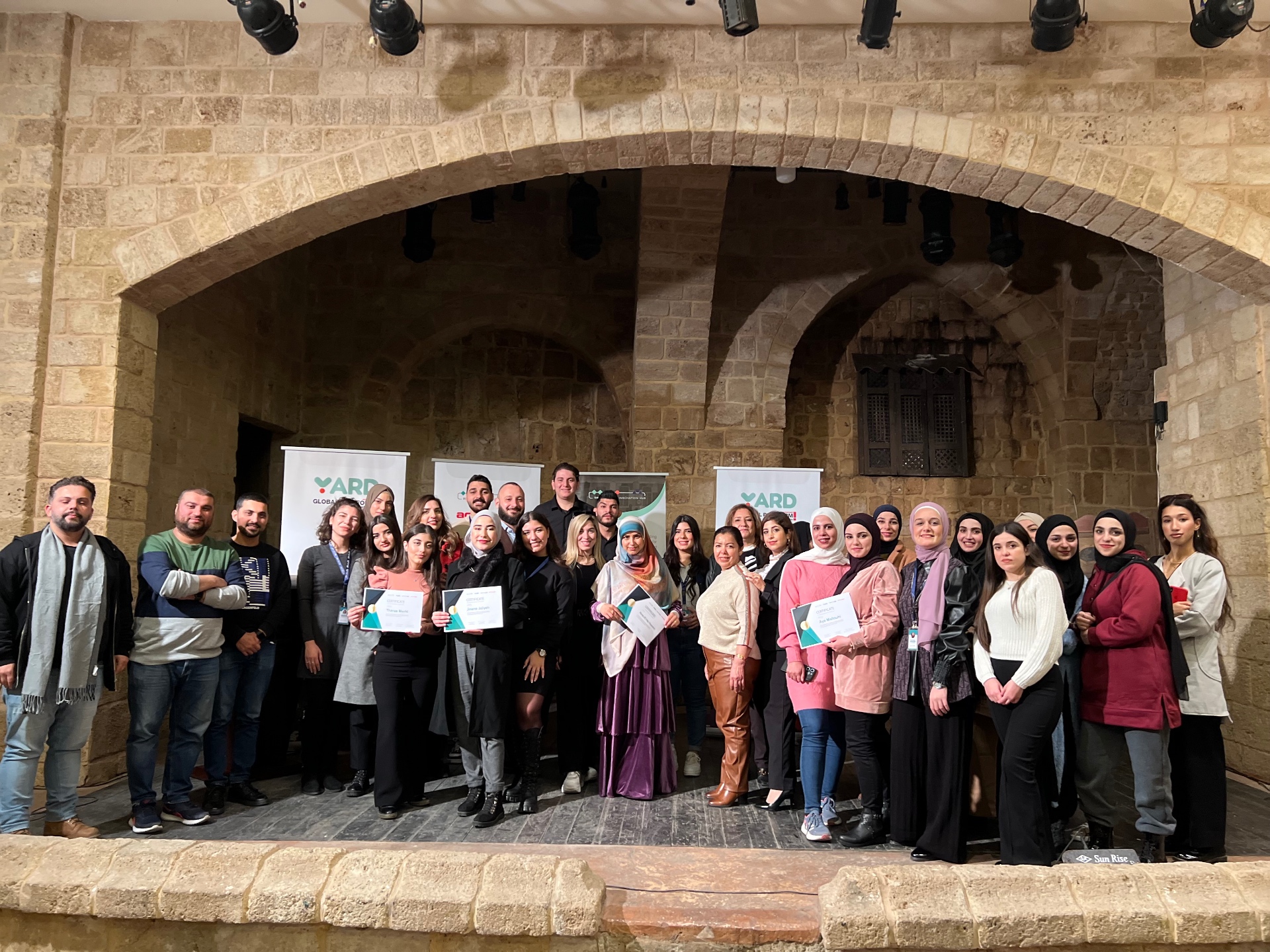 Entrepreneurship programme participants on stage holding their certificates.